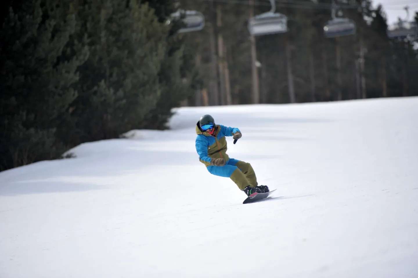 Kask, gözlük ve kışlık tulumla Sarıkamış pistinde kayan bir snowboardcu